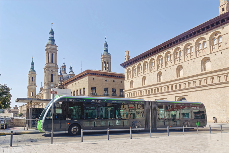 10 - A full electric articulated bus, specifically the Irizar ie tram, parked in front of the iconic Cathedral-Basilica of Our Lady of the Pillar in Zaragoza, Spain